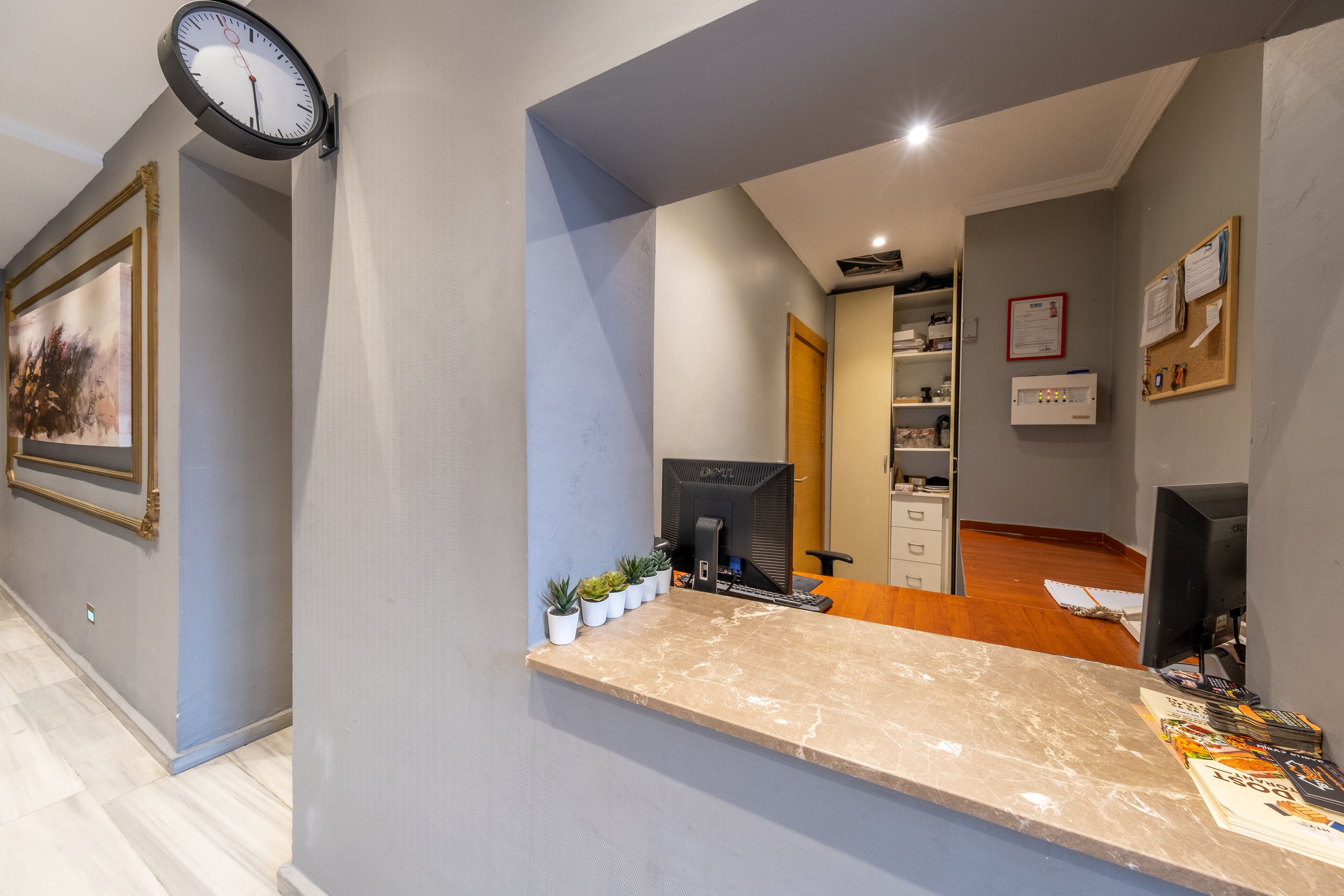 A reception area with a marble counter, a clock, a framed picture, and a bulletin board.