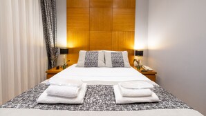 A neatly made bed with white linens and two pillows, flanked by two bedside tables with lamps and a phone. - King Suits Hotel (Istanbul)