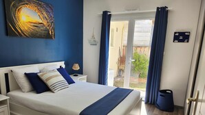 Ein Schlafzimmer mit Bett, Nachttischen, einer Lampe und Blick ins Freie.