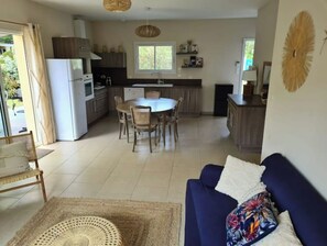 A modern kitchen with a dining area, a sofa, and a large window.