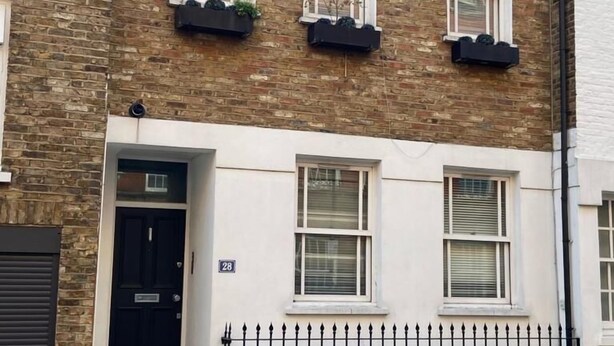 A two-story townhouse with a black front door, numbered 28, and a checkered step leading to the entrance.