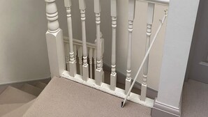 A white wooden staircase with a painting of a landscape above it.