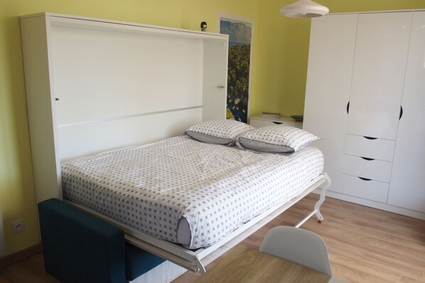 Un dormitorio con cama, mesitas de noche, armario y escritorio.