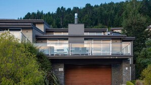 A modern two-story house with a garage, large windows, and a chimney. - Alpen View Villa | Short walk to town (Queenstown)