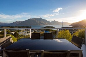 A balcony with a table and chairs overlooking a lake and mountains. - Alpen View Villa | Short walk to town (Queenstown)