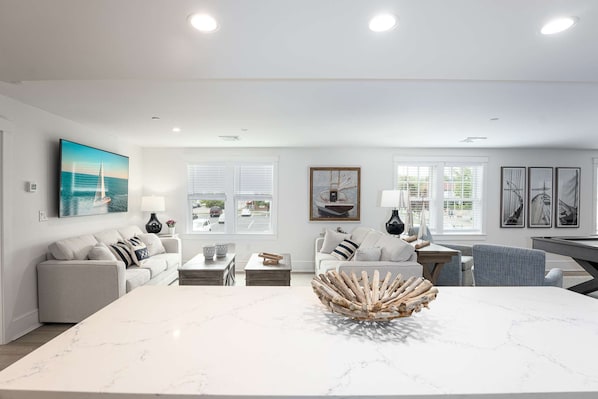 Una sala de estar moderna con una mesa de centro de mármol, sofás y una zona de comedor.