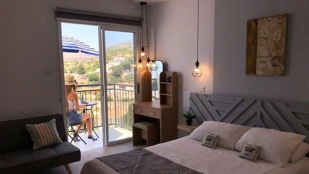 Un dormitorio con una cama grande, un sofá, un escritorio y un balcón con vistas.