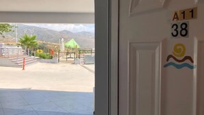 Entrada de un hotel con vistas a una zona ajardinada, que incluye una estatua, palmeras y una puerta.