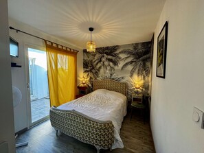 Een slaapkamer met een bed, een plafondventilator, een wandlamp en een deur naar een balkon.