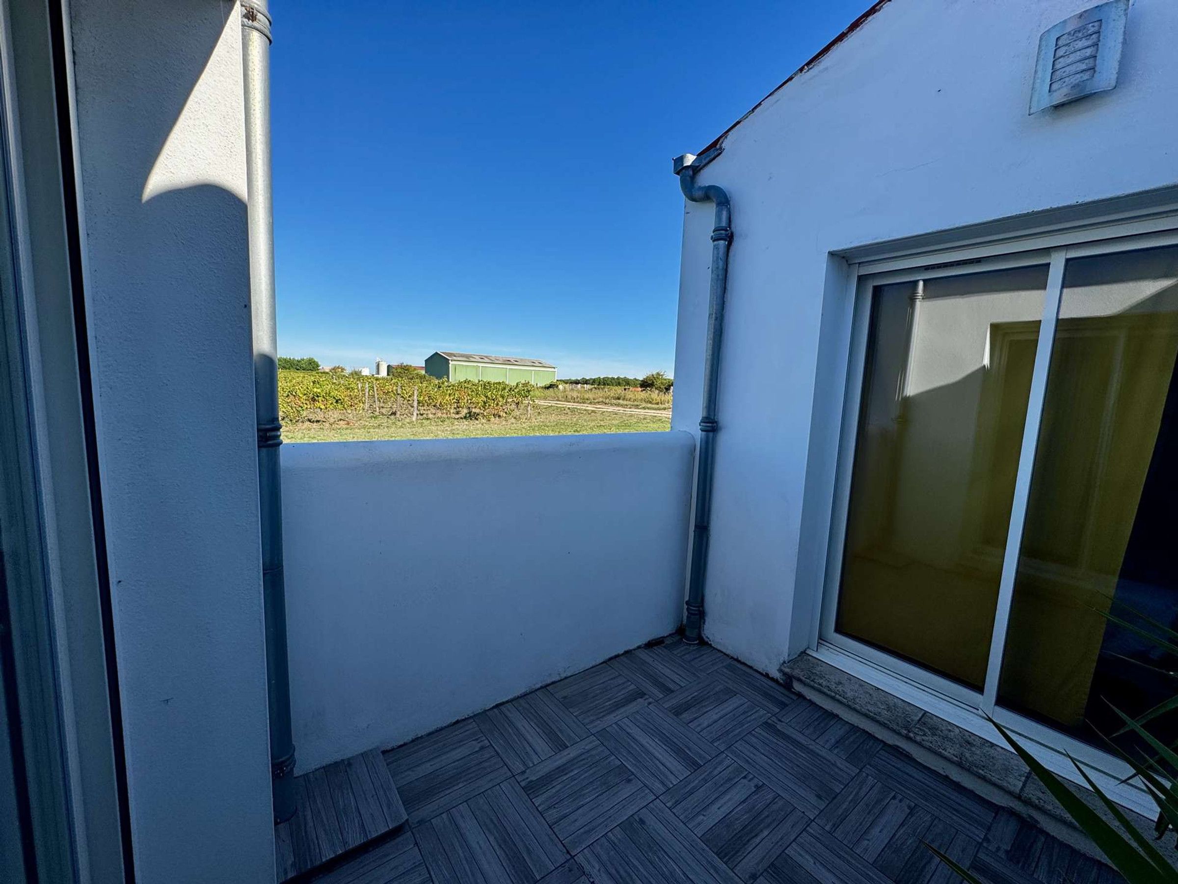 A balcony with a view of a green building and a clear blue sky.