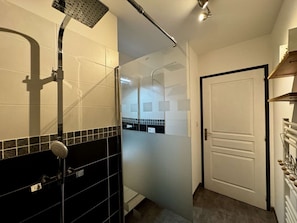 Un baño con ducha, inodoro con cerramiento de vidrio y una puerta blanca.