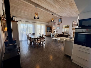 Amplia sala de estar con mesa de comedor, sofás y área de cocina con horno Bosch.