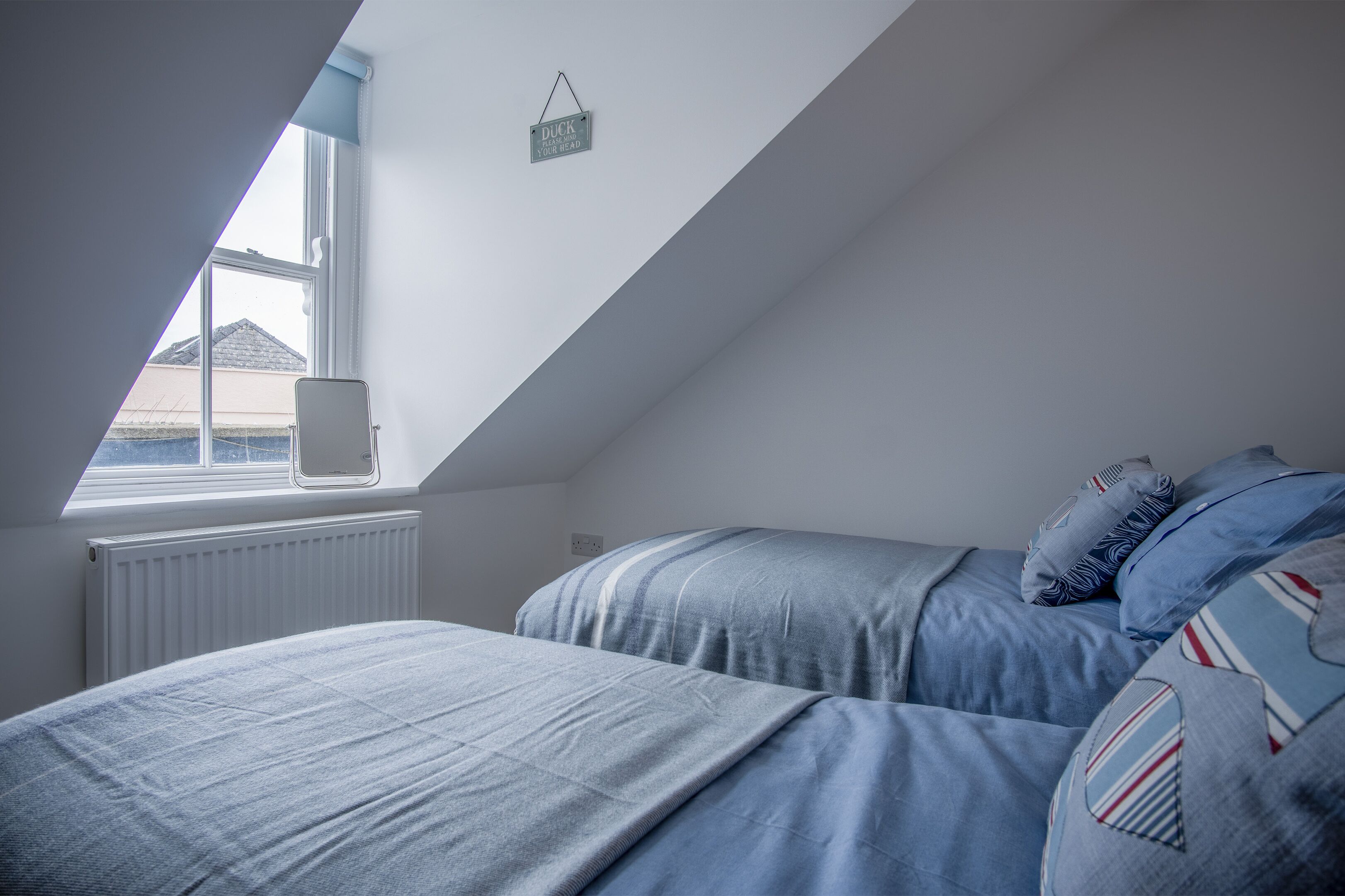 Un dormitorio con techo inclinado, una ventana y un radiador.