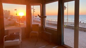 Ein Zimmer mit Blick auf den Sonnenuntergang über dem Meer, ein Sessel, ein Tisch und ein Teleskop.