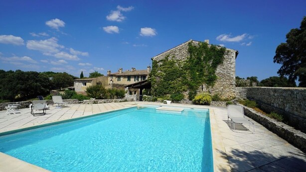 A rectangular pool with clear blue water, surrounded by stone walls and a stone building with a sloped roof. - La Grange Domaine de la Blaque (Varages)