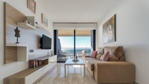 Un salon moderne avec un grand téléviseur à écran plat, un canapé beige et une bibliothèque.