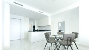 Une cuisine moderne avec des armoires blanches, un plan de travail noir et un évier en acier inoxydable.