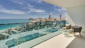 A balcony with a glass railing overlooking a cityscape and a beach. - DRIVE 128 2 Bedrooms Apartment (Benidorm)