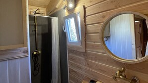 A wooden cabin bathroom with a shower, sink, and a small window. - Roulotte in the heart of the low gorges of the verdon (Quinson)