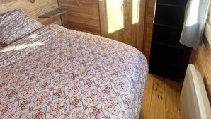 A wooden cabin room with a bed, a window, and a radiator. - Roulotte in the heart of the low gorges of the verdon (Quinson)