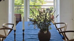 En matplats med ett bord dukat för två personer, en vas med blommor och en hängande lampa.