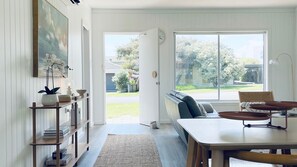 Una sala de estar moderna con un ventanal grande, un sofá, una mesa de comedor y una estantería.
