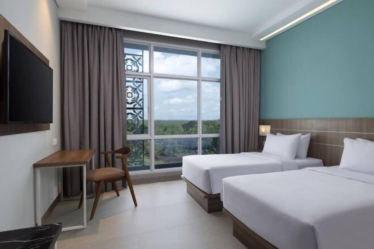 Ein Hotelzimmer mit zwei Betten, einem Schreibtisch, einem Stuhl und einem Fernseher.