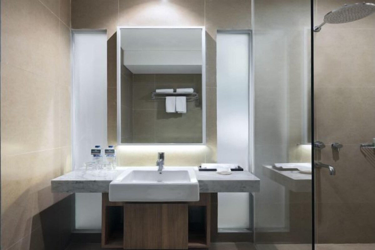 Een moderne badkamer met een grote spiegel, twee wastafels en een douchegedeelte.