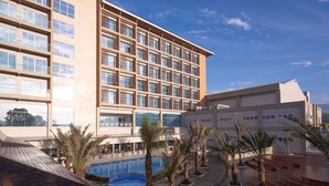 A hotel with a large pool, palm trees, and a playground. - Hotel Santika Gunungkidul (Playen)