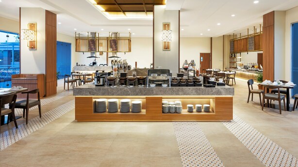 A modern hotel lobby with a central bar area, seating arrangements, and a view of the cityscape. - Hotel Santika Gunungkidul (Playen)