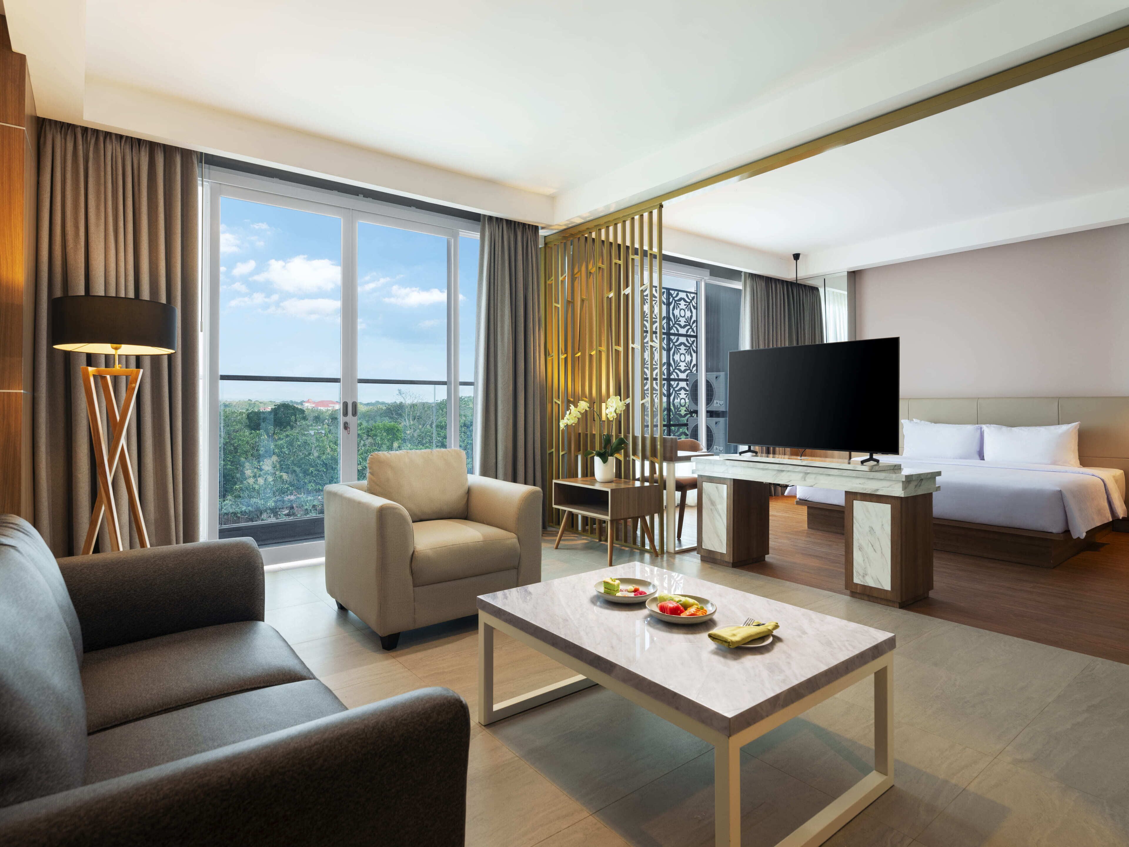 A hotel room with a bed, a TV, a desk, a coffee table, and a sofa.