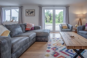 Un salon avec un canapé gris, une table basse en bois et un tapis coloré.
