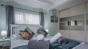 Una camera da letto con un letto, un comodino, un armadio e una finestra con tende.