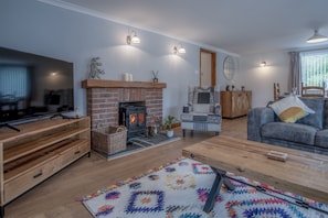 Un salon chaleureux avec une cheminée, un téléviseur et un coin salon confortable.