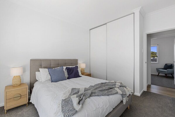 A bedroom with a bed, nightstands, a wardrobe, and a view of another room. - Tailem Retreat (Tailem Bend)