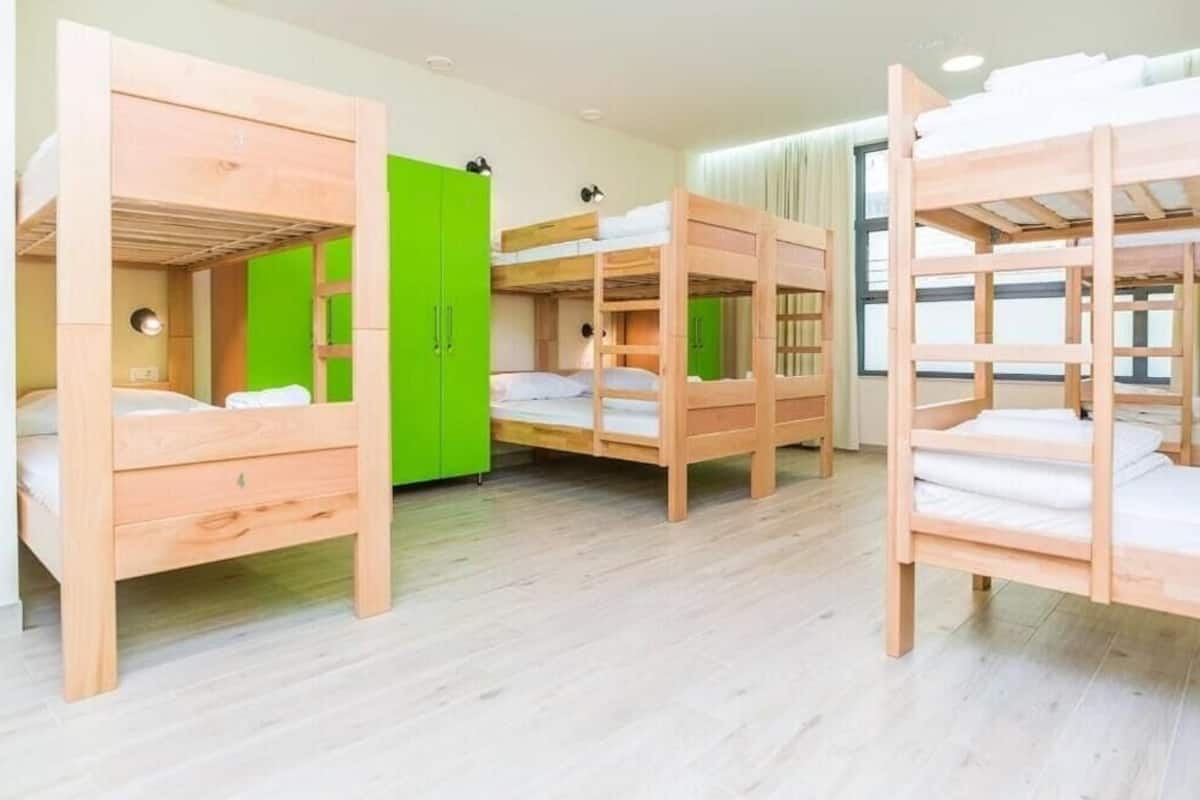 A room with bunk beds, a green wardrobe, and a window with curtains.