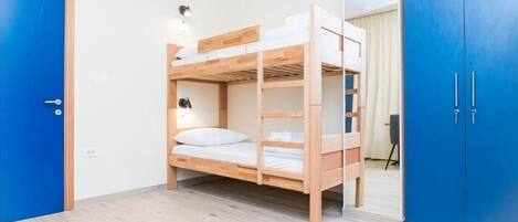 Dormitorio con literas, un armario azul y una puerta.