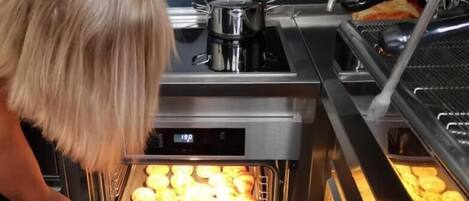 A commercial kitchen with a stainless steel oven containing baked goods.