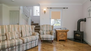 A living room with a sofa, armchair, wooden table, and a fireplace. - Viewpoint (Kendal)