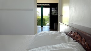 A bedroom with a bed, a view of the outdoors, and a door leading outside. - Apartment (Willemstad)