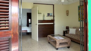 A room with a bed, a sofa, a small table with a magazine, a wooden cabinet, and a ceiling fan. - Apartment (Willemstad)