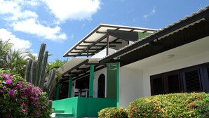 A building with a covered porch, green pillars, and a white exterior. - Apartment (Willemstad)