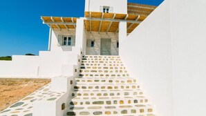 A white building with a wooden pergola and stone steps leading to a door. - Coral Villa With 4 Bedrooms in Paros (Paros)