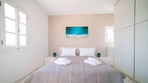A bedroom with a bed, two nightstands, a wardrobe, a painting, and a window. - Coral Villa With 4 Bedrooms in Paros (Paros)