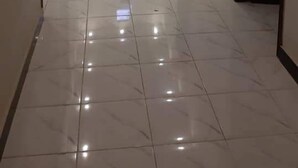 A hallway with white tiled floors, dark doors, and red and white balloons. - Hotel Royal Defence (Lahore)