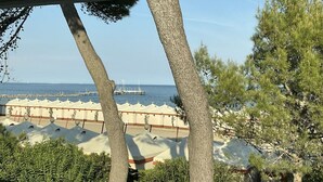 Vista de la playa con sombrillas y un muelle al fondo.