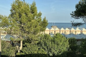 Une vue côtière avec une rangée de bâtiments blancs aux toits orange, un ciel dégagé et une étendue d’eau à l’horizon.