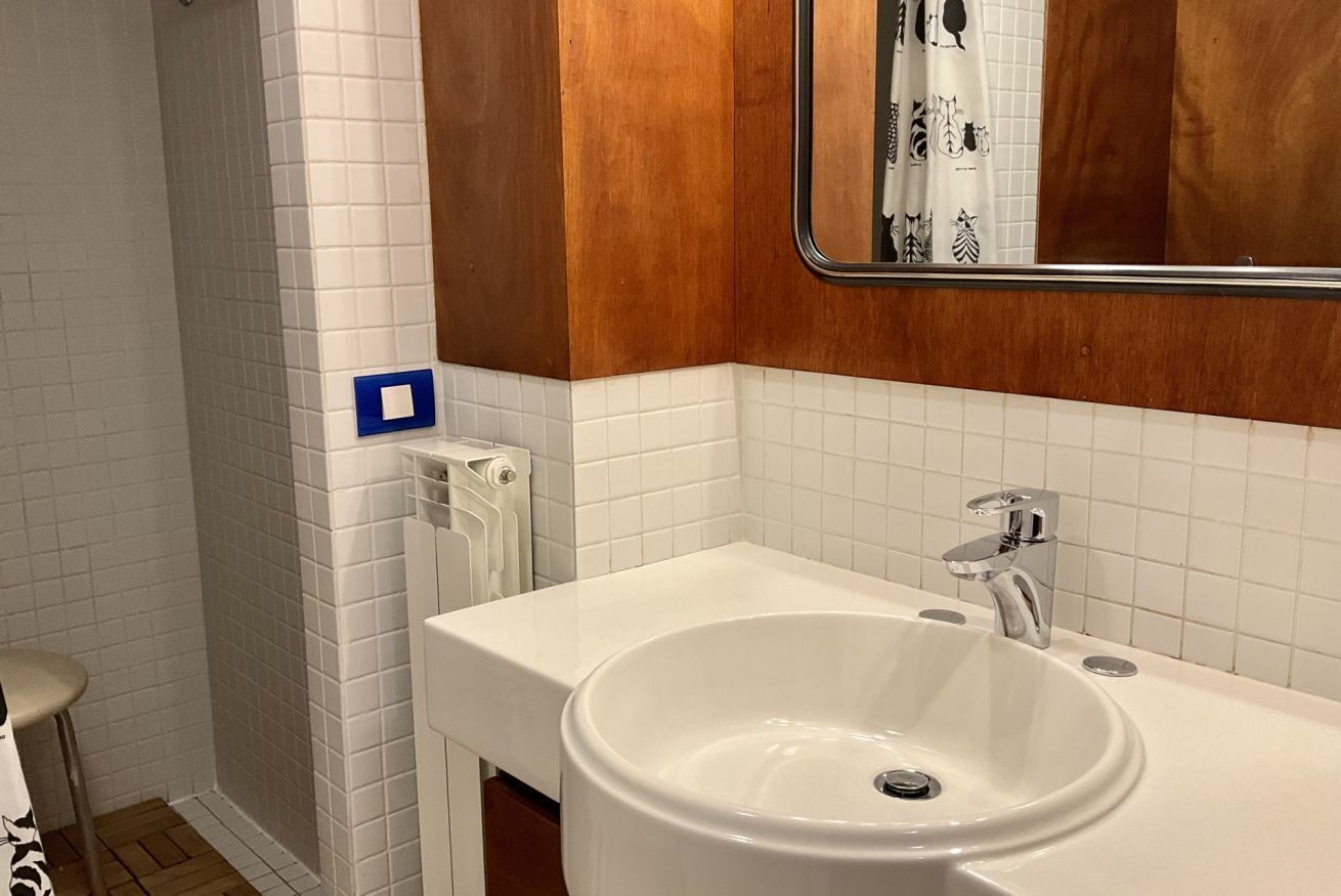 Une salle de bain avec un lavabo blanc, un miroir et un espace douche.