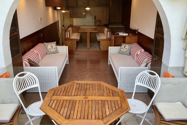Un espace de détente extérieur accueillant, avec une table en bois et des chaises en osier blanc.