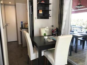 Un coin repas avec une table en bois foncé, des chaises blanches et une petite plante en pot.
